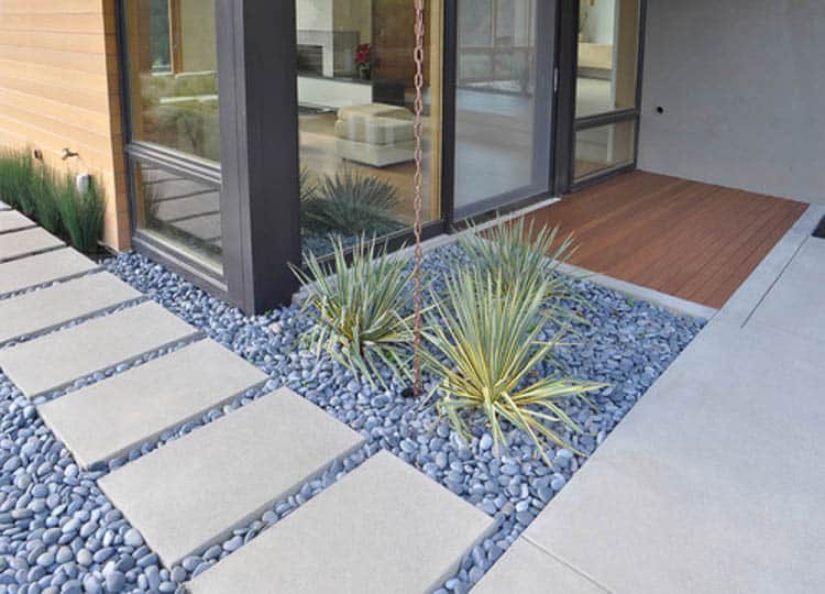 Rain chain draining into the ground in a modern landscape by Huettl Landscape Architecture