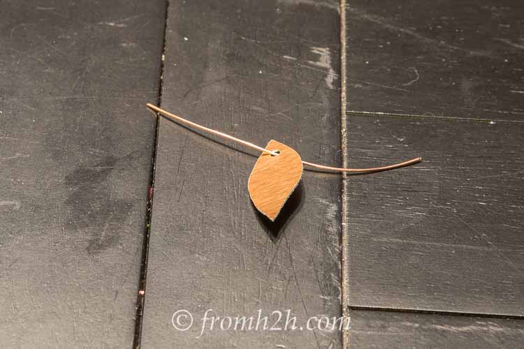 A copper leaf with a small copper wire threaded through a hole at the top