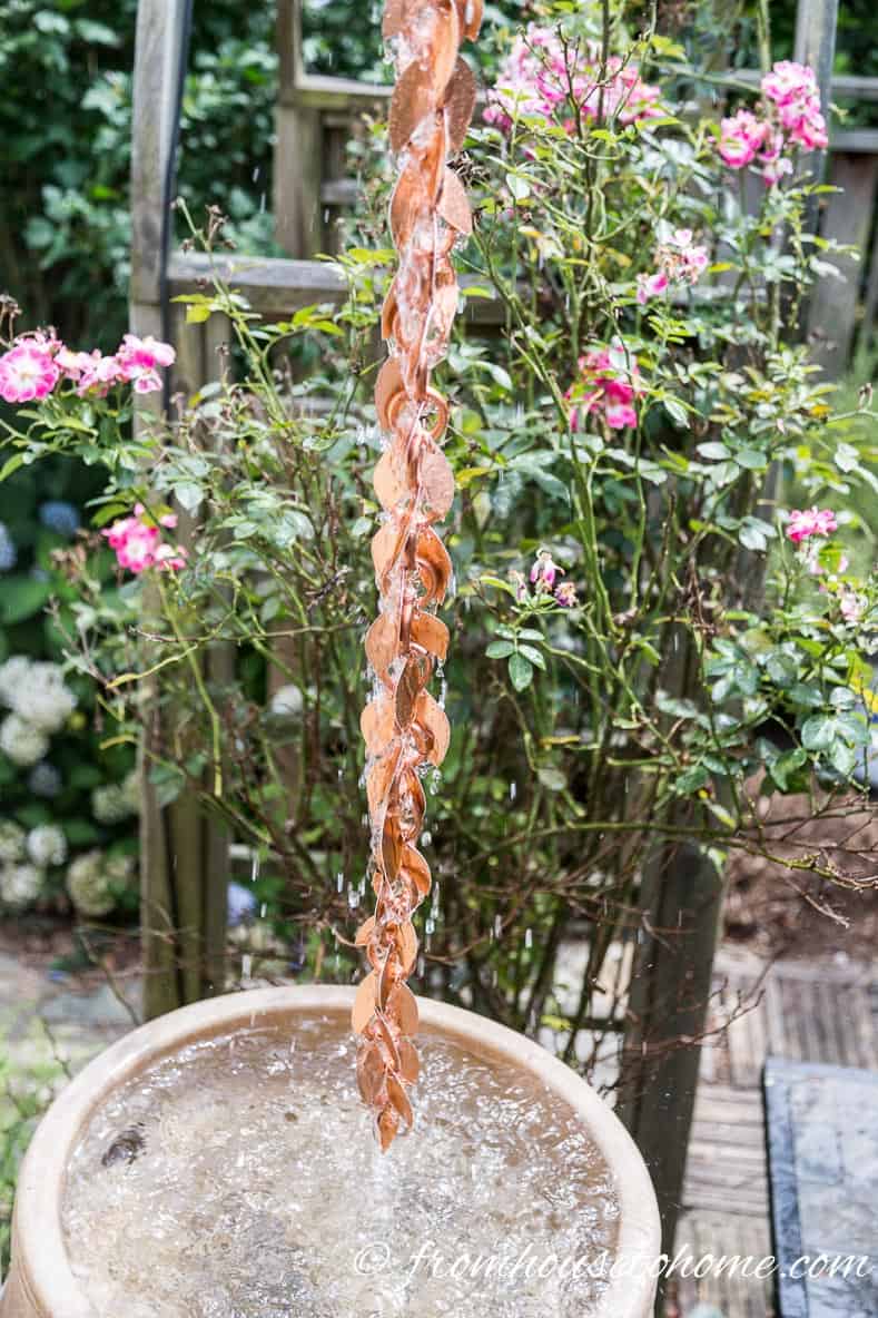 The installed rain chain hanging above a rain barrel