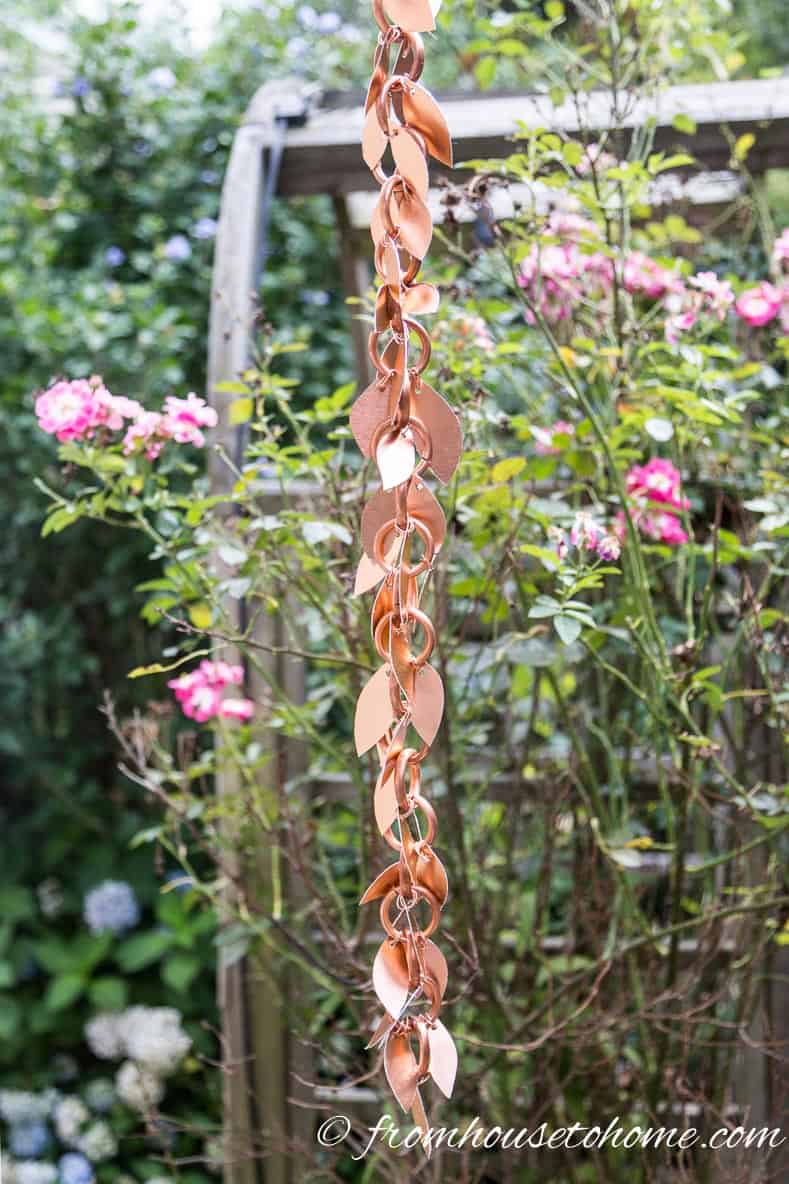The finished rain chain with leaves hanging in the garden