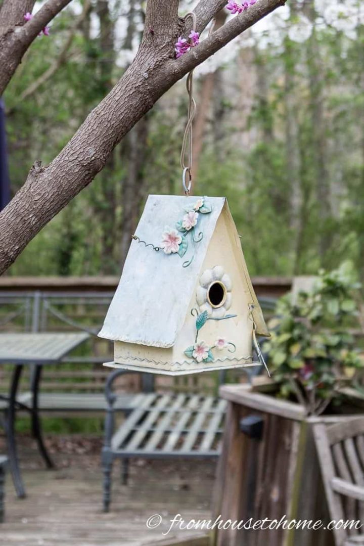 Decorated birdhouse hung from a tree in the garden
