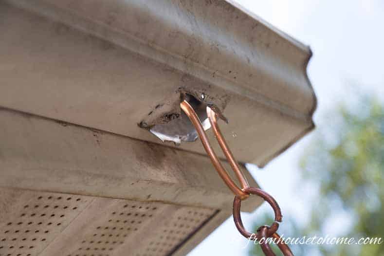 A close up of the DIY rain chain hanger attached to the gutter