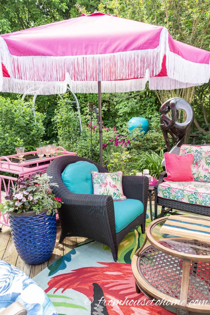 Pink umbrella with white fringe over a large outdoor arm chair