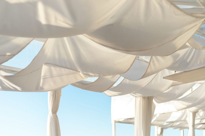 White shade sails hung loosely from a pergola