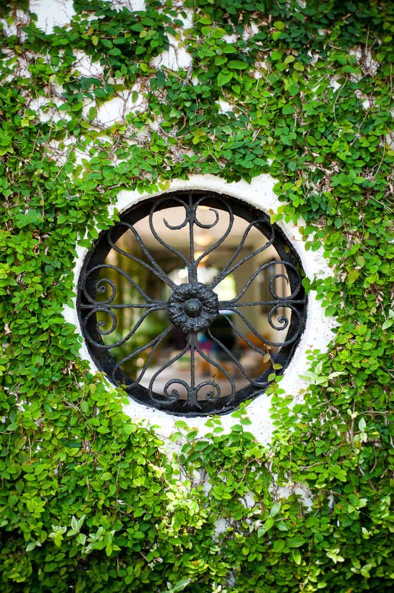 Round wrought iron window in a secret garden door looking into a private garden ©Heather Wissman - stock.adobe.com