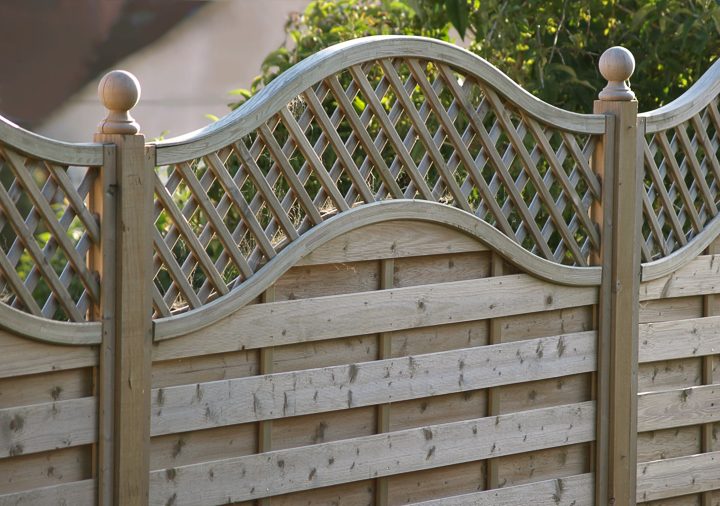 Privacy fence with horizontal wood slats and a curved lattice top 