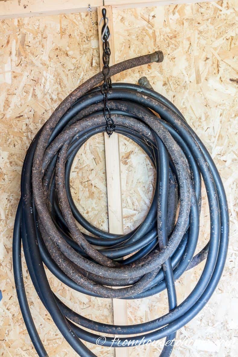 Hoses hung on a coat hook with a  chain in a shed