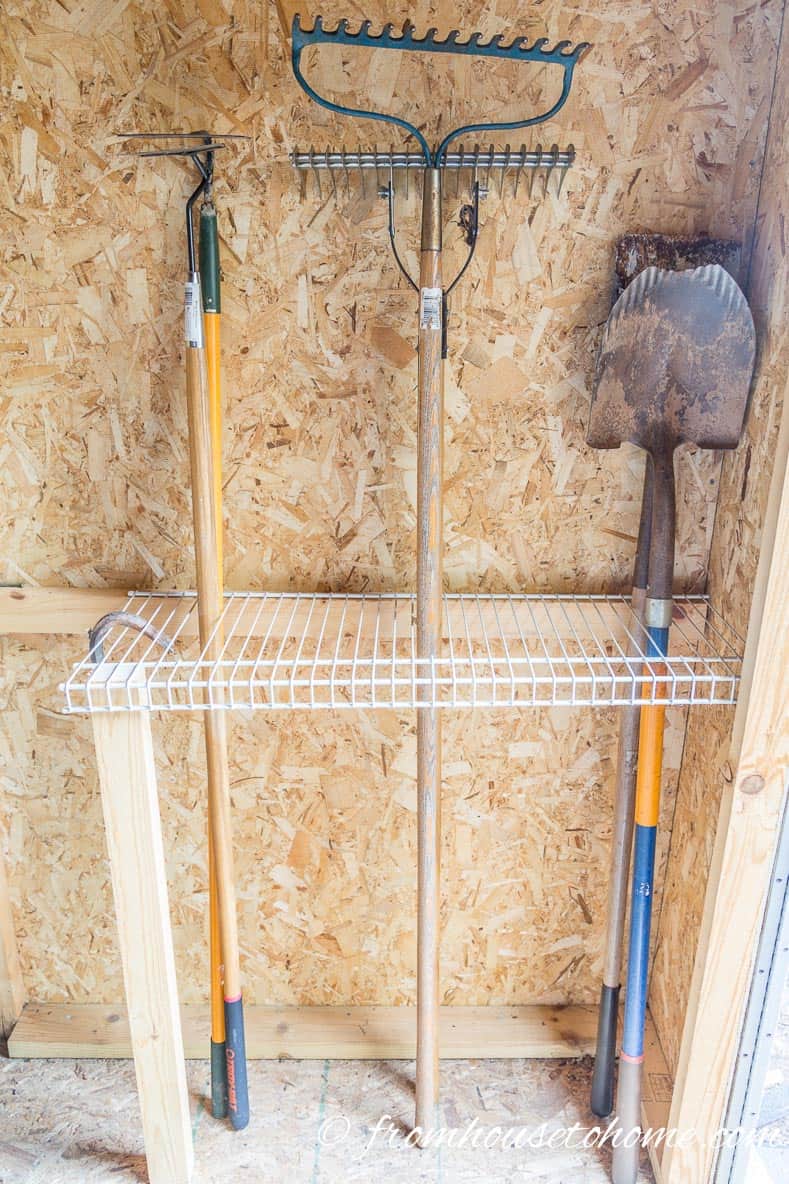 Wire shelving stores tall garden tools like rakes and shovels