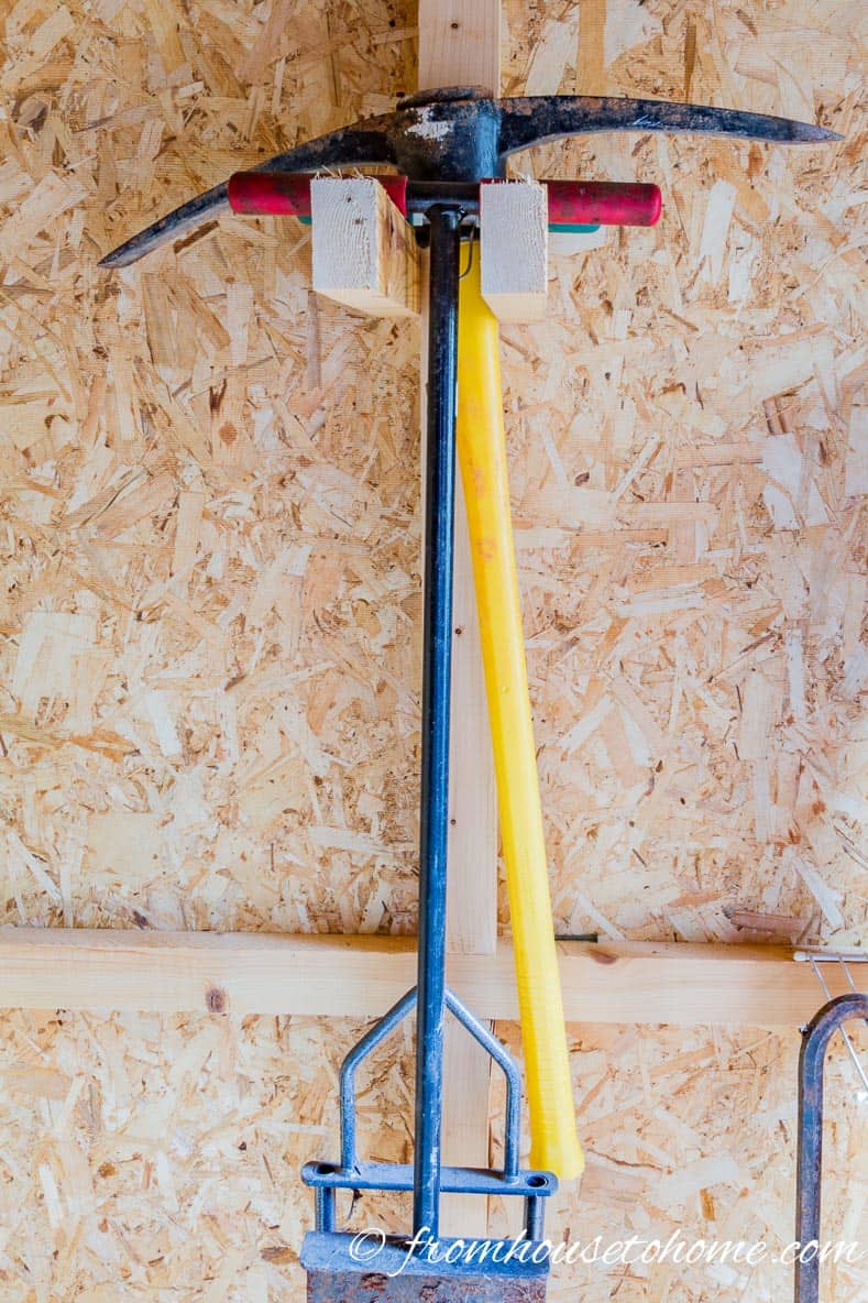 T-shaped garden tools hung on 2 - 2 x 4's attached to a wall stud in the shed