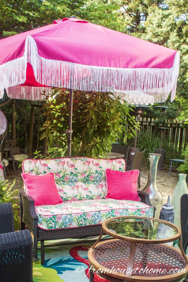 Pink patio umbrella over an outdoor sofa on a deck