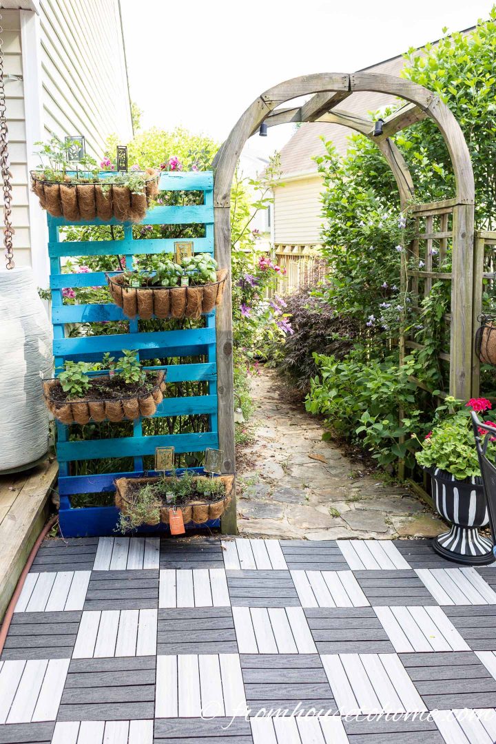 Painted DIY pallet herb garden with window boxes beside an arbor
