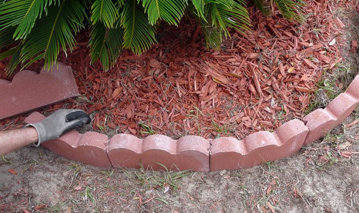 Scalloped brick edging being installed around a curved garden bed