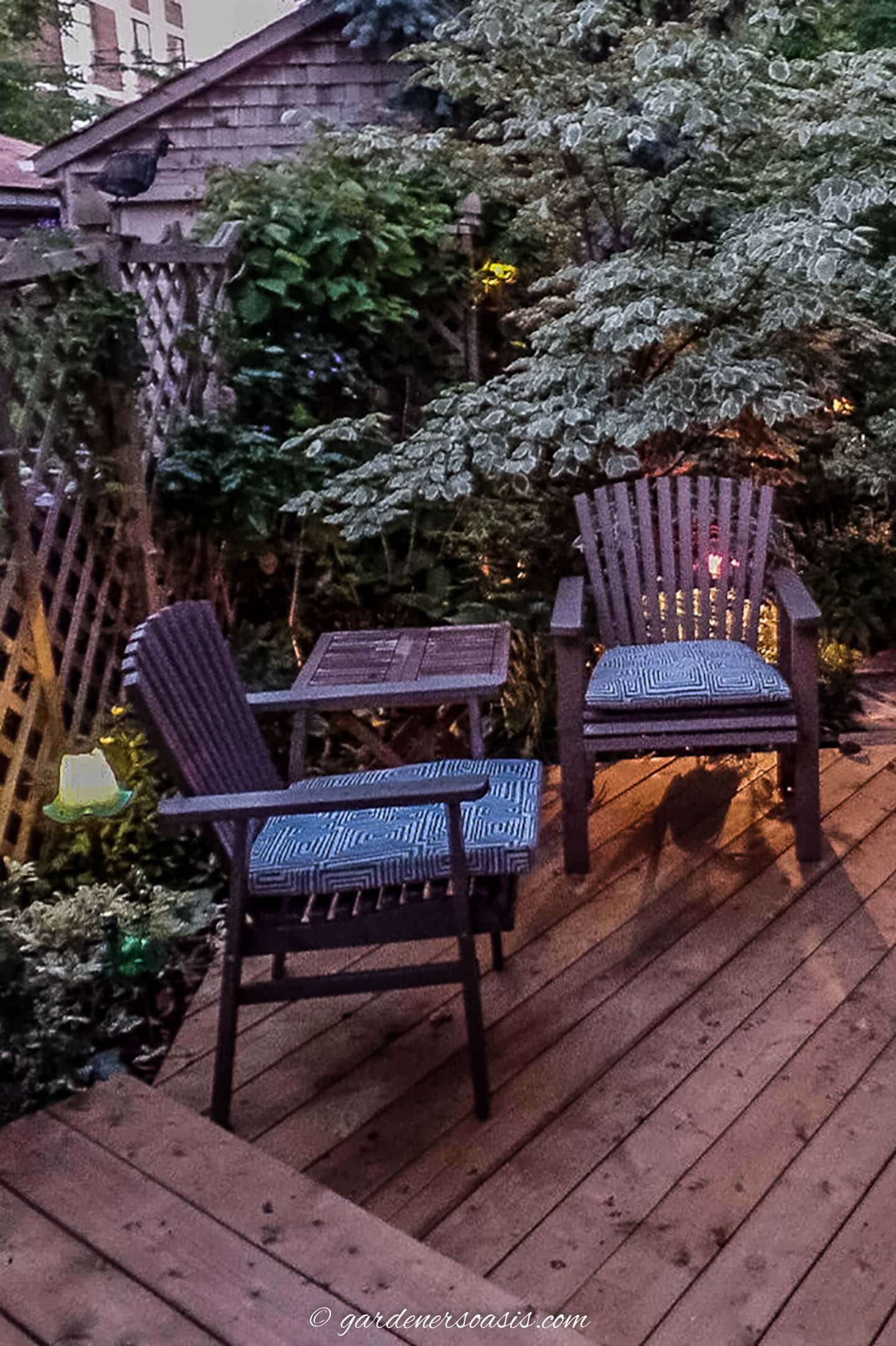 wood deck with wood chairs and a table surrounded by trees and plants