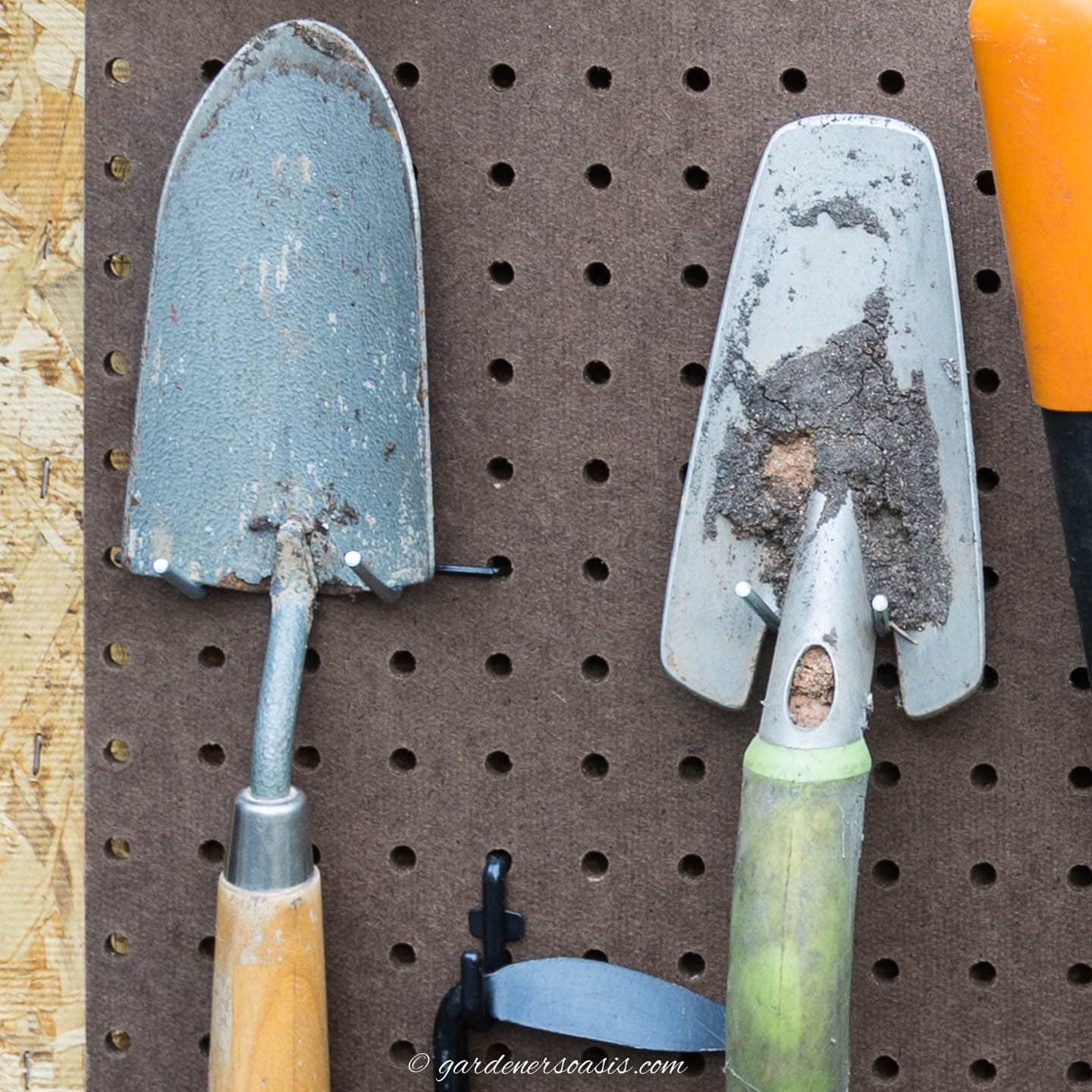 garden trowels hung on pegboard with two straight hooks