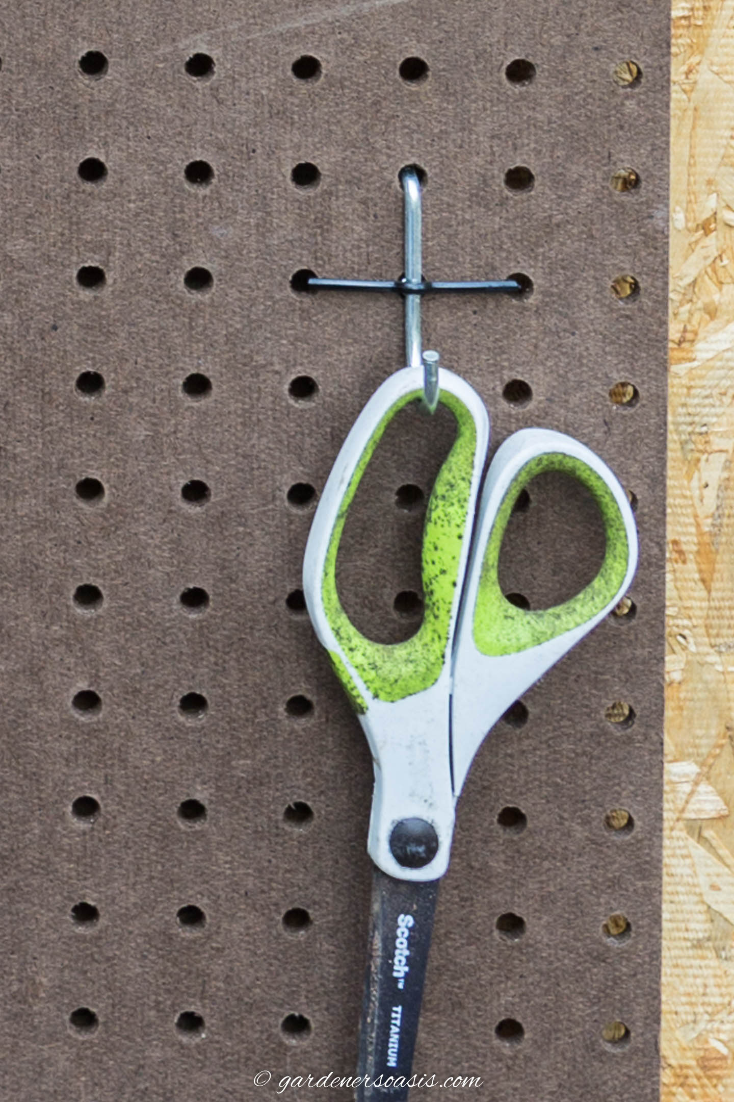 scissors hanging on a pegboard hook held onto the pegboard with a pegboard lock