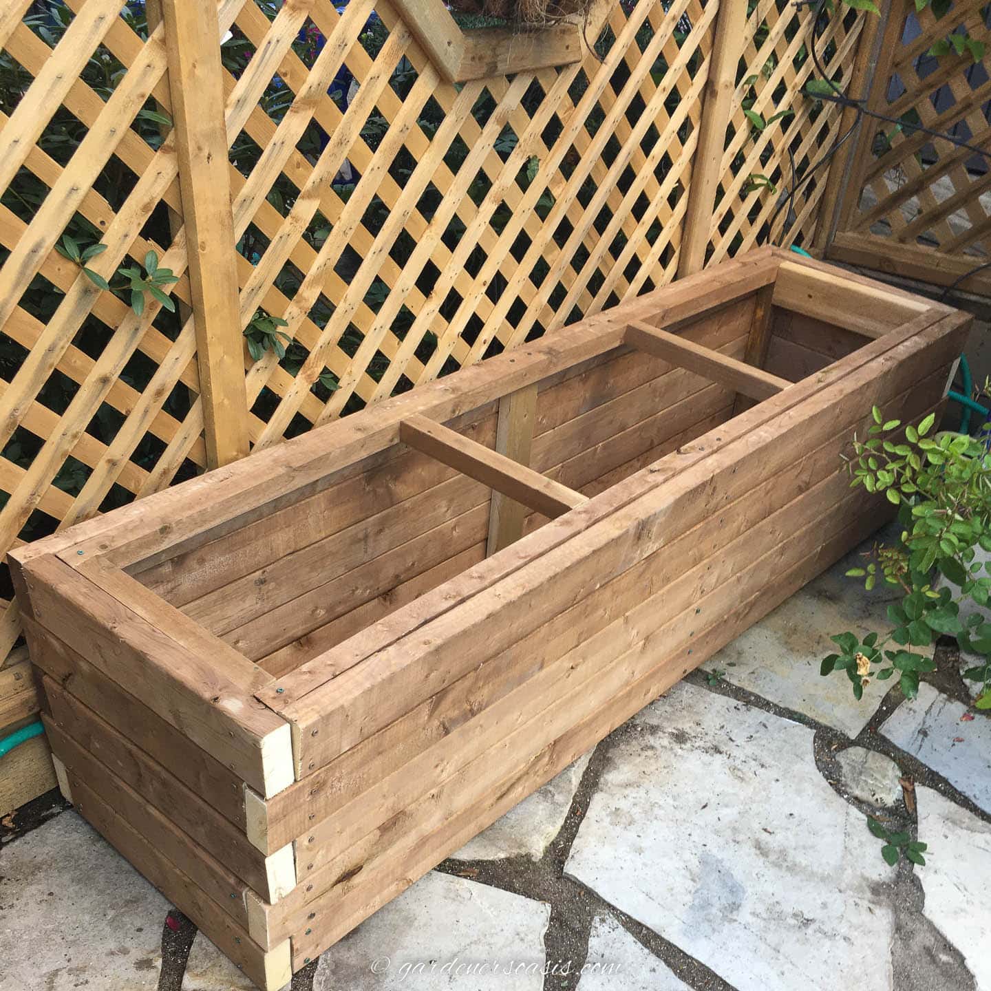 Finished DIY planter box in front of a fence