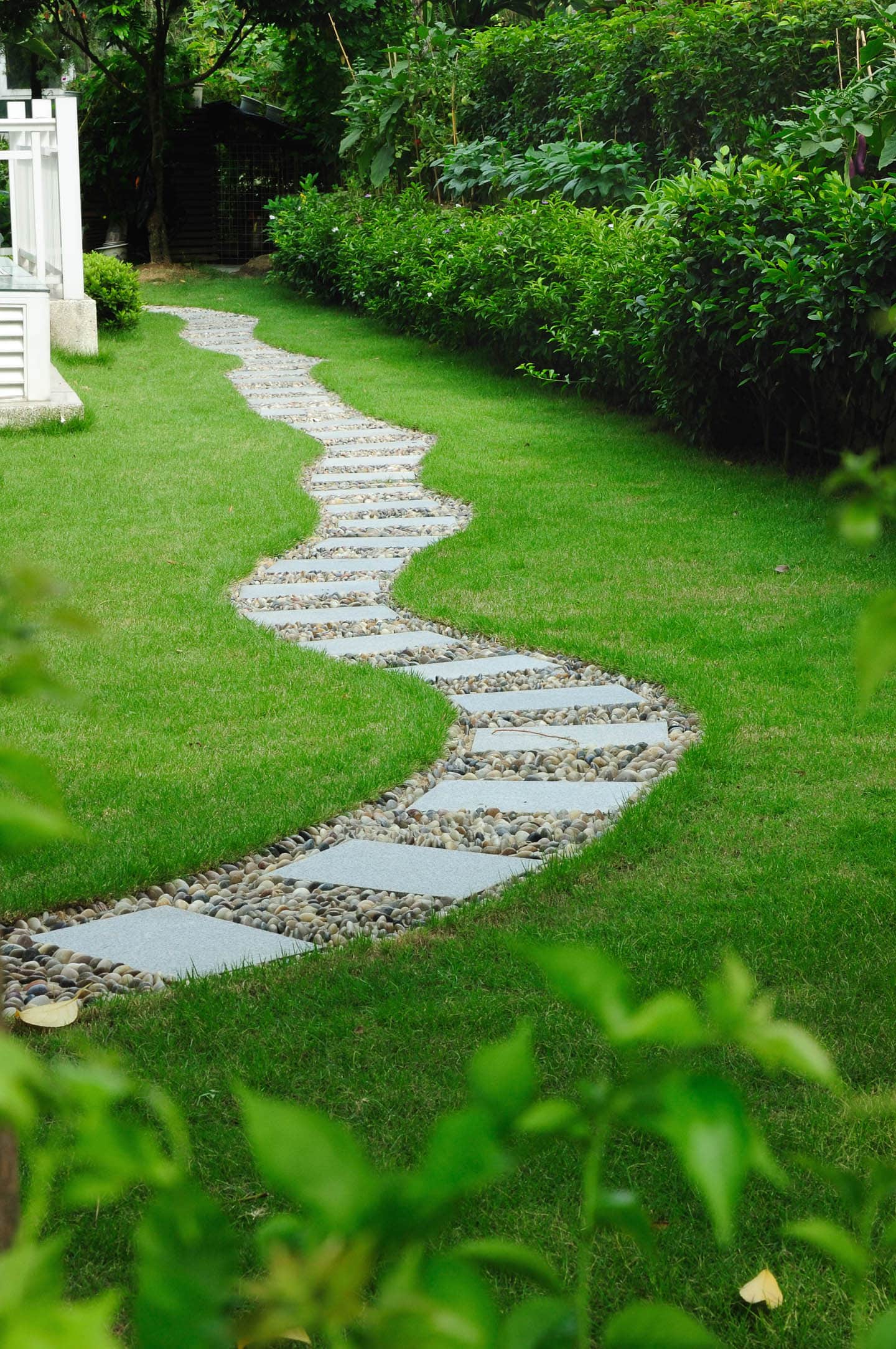 a flagstone and stone pathway through the grass in a side yard