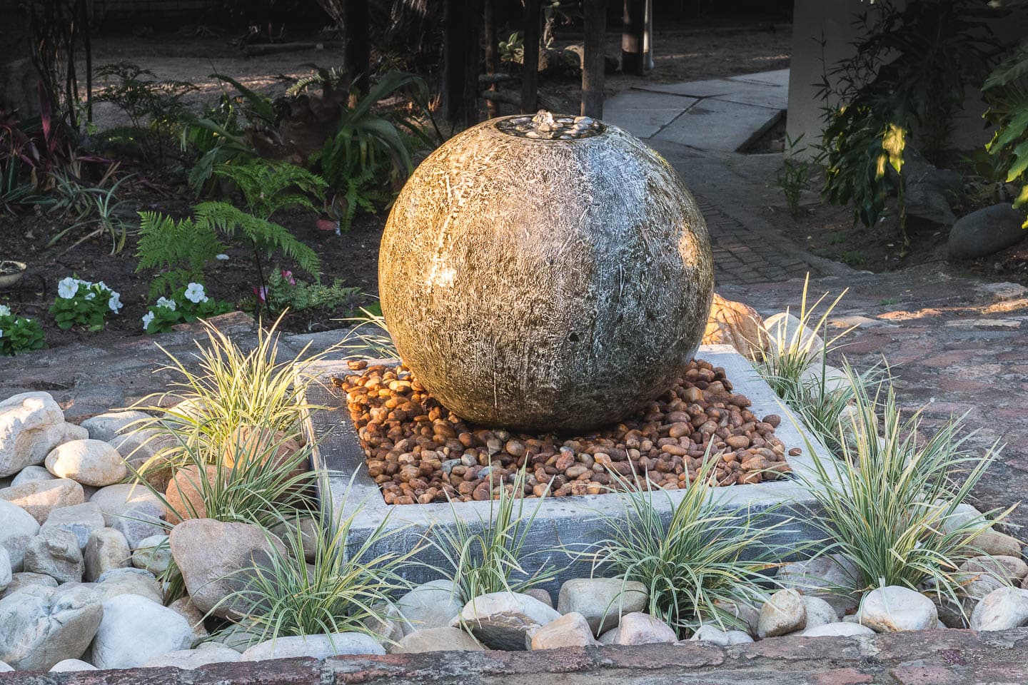 round stone water fountain bubbler in a rock garden