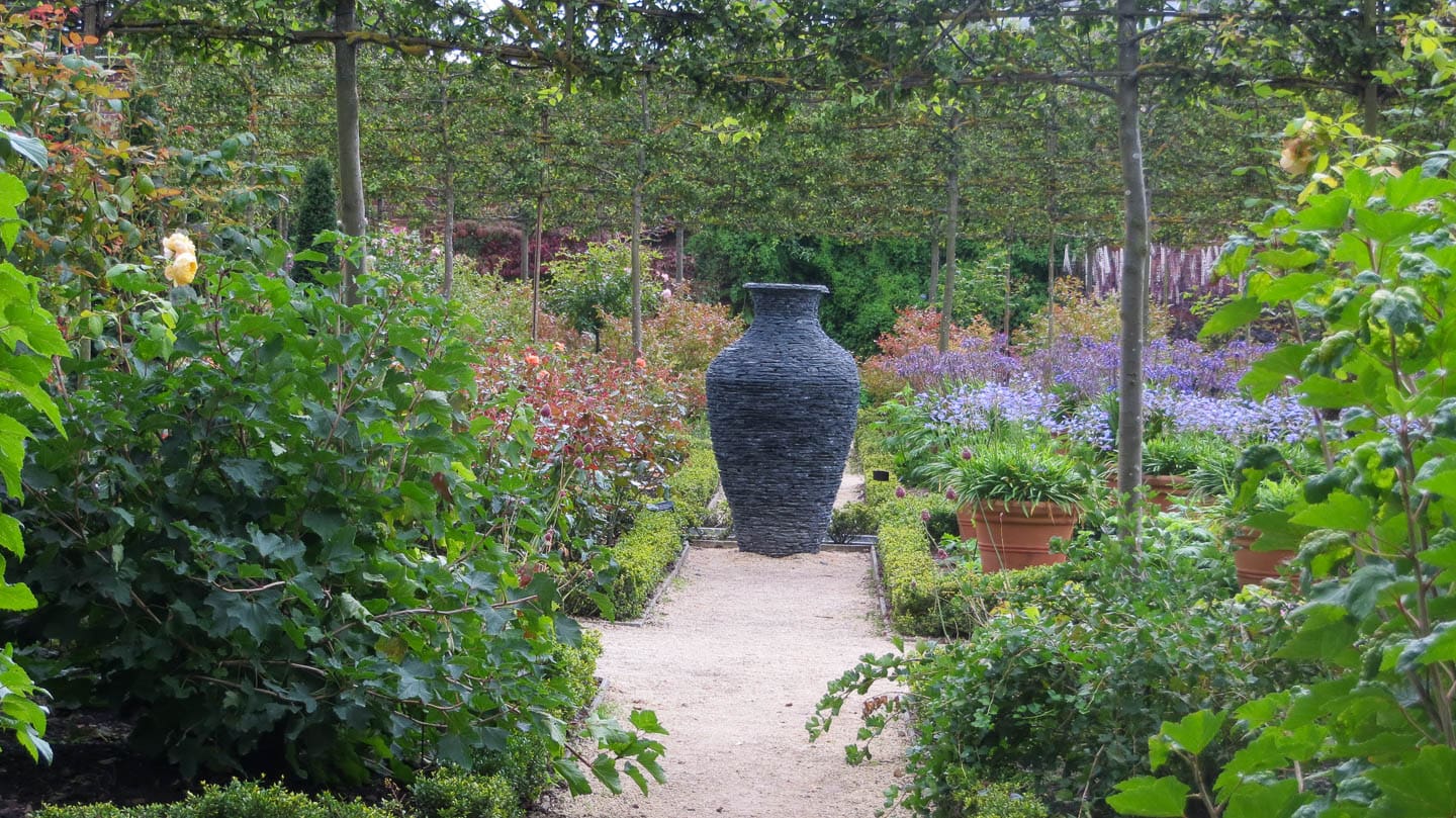 A large urn in the middle of a formal garden central pathway