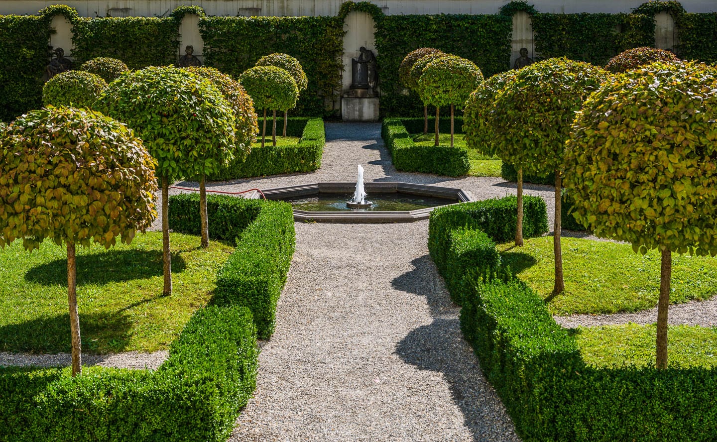 Traditional formal garden with a central path lined with clipped hedges and limbed up trees