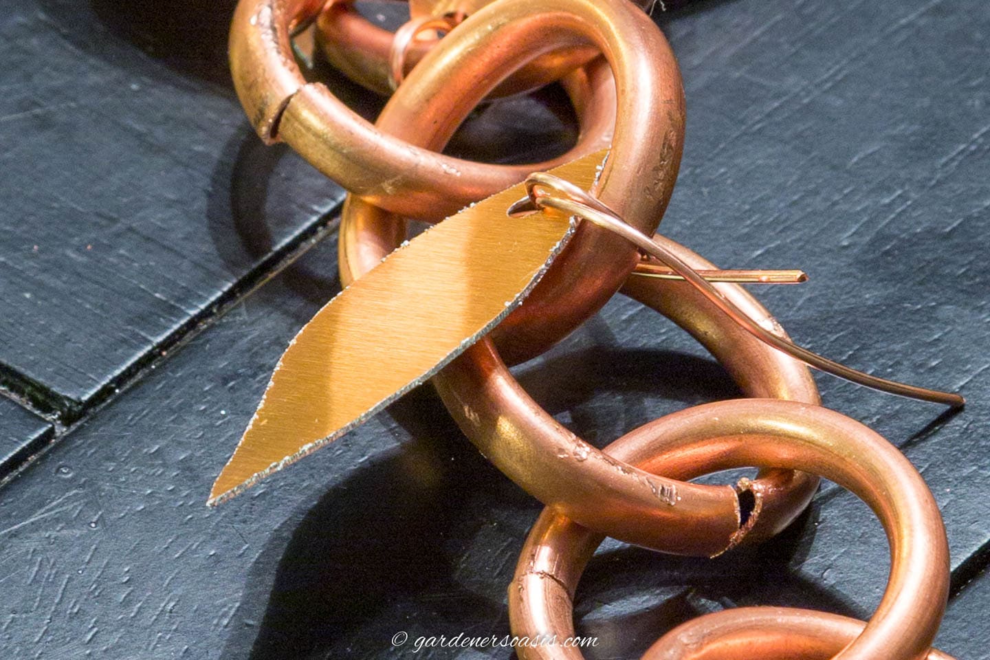 Copper leaf being attached to the DIY copper rain chain with a wire
