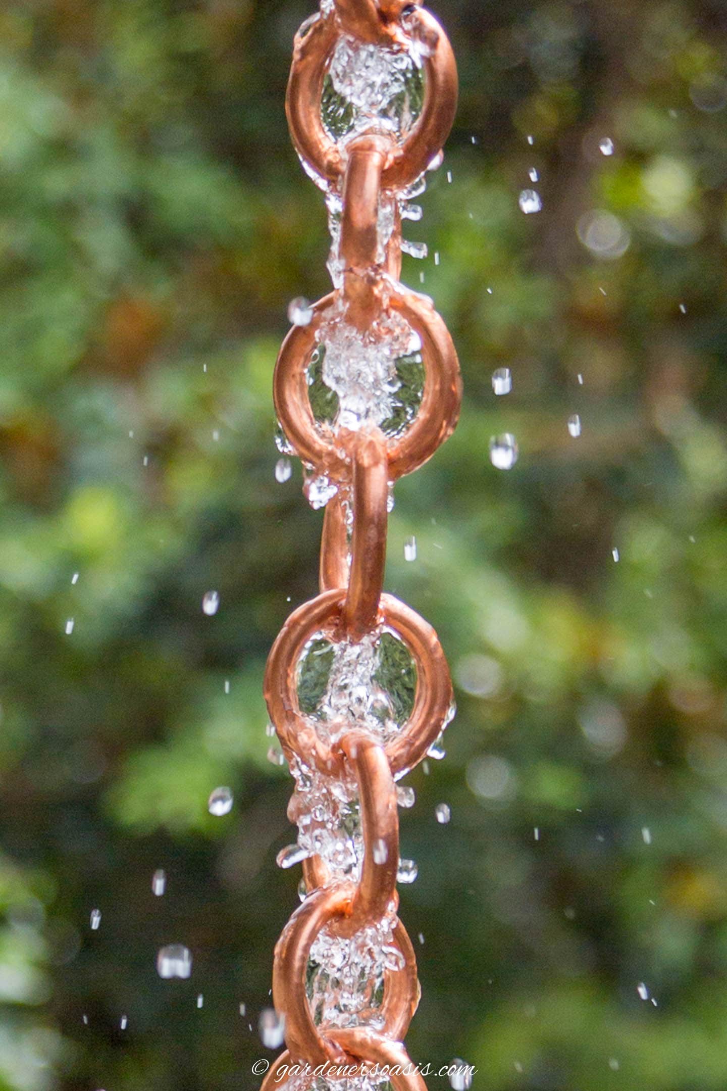Close up of the DIY copper link rain chain with water running down